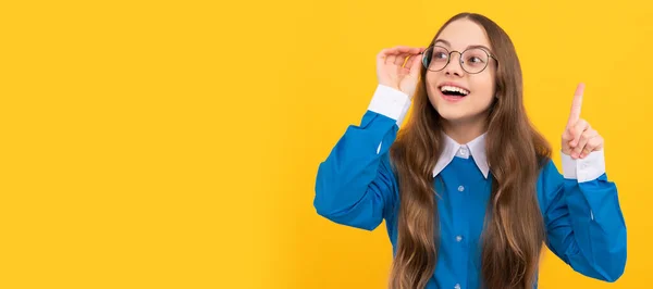 Clever idea. Clever girl in eyeglasses yellow background. School age child with raised finger. Eureka. Child face, horizontal poster, teenager girl isolated portrait, banner with copy space