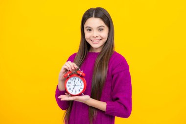 Child teenager girl with alrm clock isolated on yellow background. Time and deadline concept