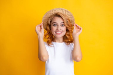 Sarı arka planda zarif hasır şapkalı güzel bir kadın.