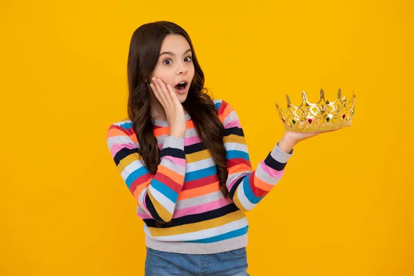 stock image Shocked amazed face, surprised emotions of young teenager girl. Teenage selfish girl celebrates success victory. Teen child in queen crown isolated on yellow background. Princess in tiara. Prom party