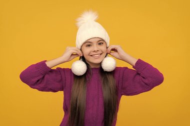 Sarı arka planda kartopları olan şapkalı neşeli çocuk, Noel..