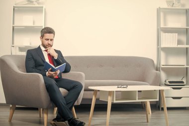 Takım elbiseli olgun iş adamı planlamacıyla ofiste oturuyor..