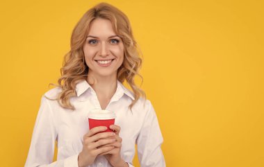 Sarı arka planda kahve fincanı olan neşeli sarışın kadın..