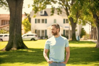 ciddi traşsız adam yeni evin yanında duruyor, emlakçı..