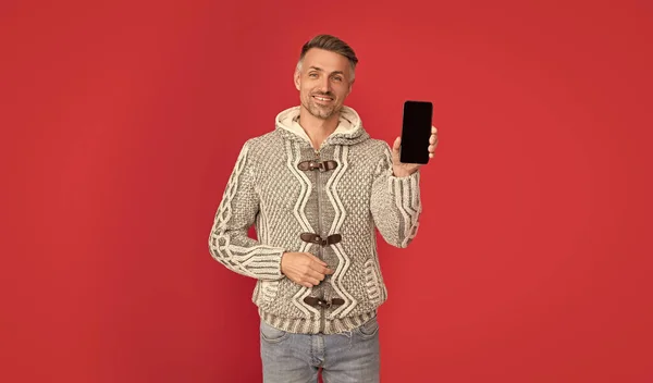 Hombre Feliz Suéter Que Muestra Pantalla Del Teléfono Fondo Rojo —  Fotos de Stock