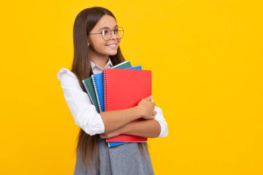 Okula dönelim. Kitabı öğrenmeye hazır ergen bir kız öğrenci. İzole edilmiş sarı stüdyo geçmişi olan liseli kızlar. Mutlu kız yüzü, pozitif ve gülümseyen duygular