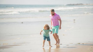 Baba oğul ve erkek çocuk kumsalda birlikte koşuyorlar, çocukluk..