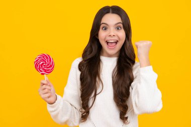 Sarı izole edilmiş arka planda lolipopu olan havalı bir genç çocuk. Tatlı çocukluk hayatı. Lezzetli lolipop şekerli genç kız. Heyecanlı genç kız