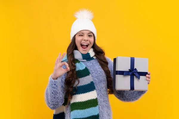 Teenager child in winter wear holding gift boxes celebrating happy New Year or Christmas. Winter kids holiday. Excited face, cheerful emotions of teenager girl