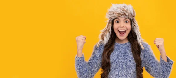 黄色の背景にニットを着た10代の女の子 暖かい服を着た子供の肖像画です 冬の帽子の子供の女の子のバナー コピースペースのあるスタジオポスターヘッダー — ストック写真