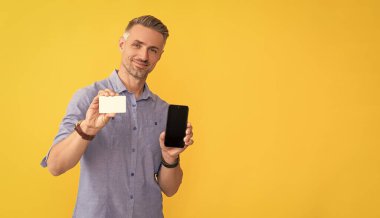 Kredi kartı ya da banka kartı. Adam internet bankacılığı ile ödeme yapıyor. Alışveriş uygulaması. Siber pazartesi. Hızlı ödeme. Neşeli adam akıllı telefon gösterdi. Müşteri internet parasını cep telefonunda kullanıyor. gösterim kartviziti.