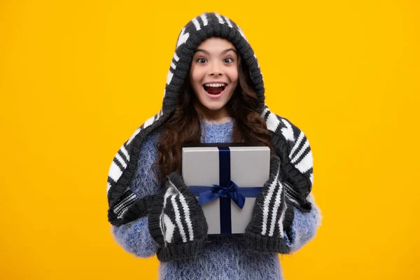 Teenager child in winter wear holding gift boxes celebrating happy New Year or Christmas. Winter kids holiday. Happy teenager, positive and smiling emotions of teen girl