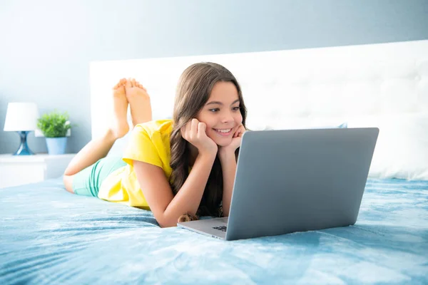 在笔记本电脑上工作的少女躺在床上 躺在卧室里休息 积极向上 面带微笑 — 图库照片