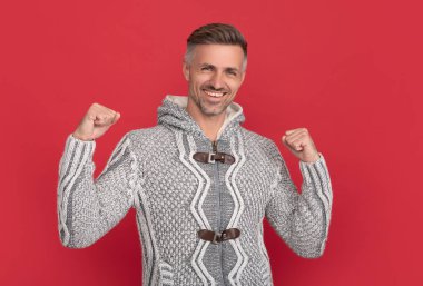 Kırmızı arka planda gri kazaklı mutlu adam, moda..