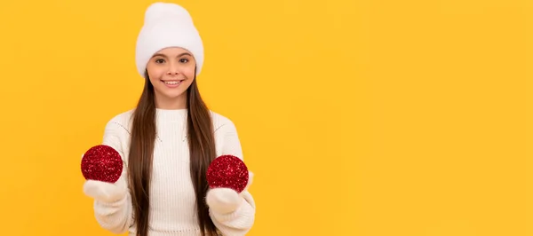 冬の女の子 冬の帽子と手袋の幸せな子供は黄色の背景に装飾的な新年のボール クリスマスを保持します クリスマスの子供の女の子のバナー スタジオの子供の冬の肖像画とともにコピースペース — ストック写真