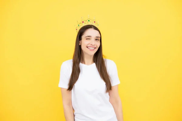 Portrait of woman queen. Gorgeous girl with crown. Party celebration concept. Close-up portrait of charming smiling lovely girl holding queen crown, yellow background