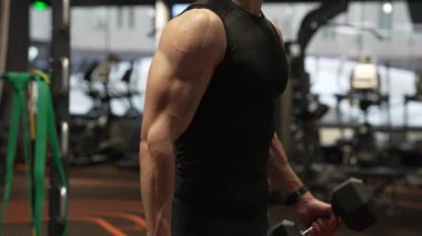 Spor salonunda spor salonundaki dambıllarla pazı egzersizi yaparken, fitness ekini manzarası. Spor salonunda fitness egzersizi. Spor salonunda spor yapan adam.
