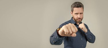 Olgun adam yumruklarını sıkıca kavrayarak dövüş pozisyonunda duruyor. Günlük iş tarzı, rekabet. İnsan yüzü portresi, kopyalama alanı olan pankart