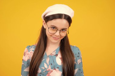 Sarı arka planda çocuk stüdyosu portresi. Çocukluk yaşam tarzı konsepti. Sevimli ergen kız yüzünü yakından çek. Mutlu ergen, pozitif ve gülümseyen duygular