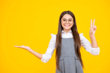Onun yakın plan portresi. Güzel, çekici, neşeli, şaşkın kız, sarı arka planda izole edilmiş fotokopi alanını işaret ediyor. Kopyalama alanını düzenle