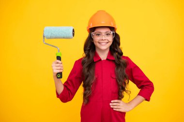 Atölyedeki ressam. Yenileme ve onarım. Kasklı, fırçalı genç bir kız. Kasklı çocuk. İnşaat alanında boyacı çocuk. Genç kızın mutlu ve gülümseyen duyguları