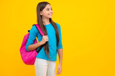 Okul üniformalı okul çantalı kız. Liseli gençler sırt çantalarını sarı izole edilmiş arka planda tutarlar. Mutlu ergen portresi. Gülümseyen kız