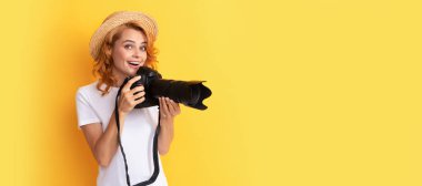 Hayret bir kız fotoğraf makinesini tutuyor. Amatör ve profesyonel fotoğrafçılık. İzole edilmiş yüz portresi, taklit alanı olan pankart