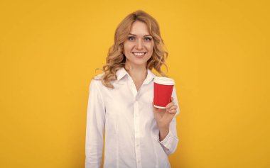 Sarı arka planda kahve fincanı olan neşeli sarışın kadın..