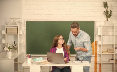 Okulda konsantre baba ve çocuk eğitimi. Laptop karatahta arka planda, çocukluk..