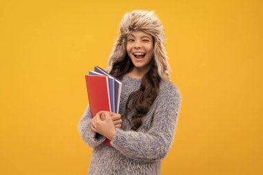 Sarı arka plan ve bilgi defteriyle uzun şapkalı mutlu çocuk..