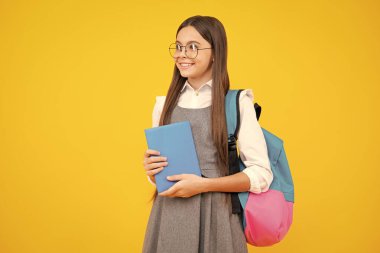 Okula dönelim. Liseli kız, sarı izole stüdyo geçmişi üzerine kitap tutuyor. Okul ve eğitim kavramı. Okul üniformalı ergen kız.