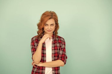 Mavi arka planda kareli gömlekli, kızıl saçlı, çapkın bir kadın..