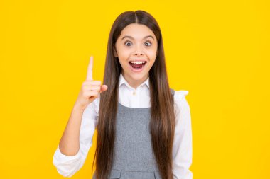 Heyecanlı bir yüz. Kendine güvenen ve başarılı genç çocuk izole edilmiş sarı arka planda ve bir numaralı parmağı işaret ediyor. Çocuğun iyi bir fikri var.