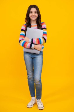 Heyecanlı bir yüz. Sarı arka planda izole edilmiş günlük kıyafetlerle dizüstü bilgisayarı olan zeki bir çocuk. Mutlu ergen, pozitif ve gülümseyen liseli kız duyguları