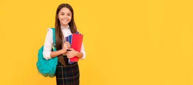 Sırt çantalı ve okul üniformalı gülümseyen çocuk sarı arka planda, eğitimli. Öğrenci pankartı. Kopya alanı olan öğrenci portresi