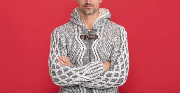 grizzled guy in sweater on red background. hoary man portrait. male fashion model crossed hands. winter fashion. mens beauty. hair and skin care. copy space.