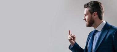 Takım elbiseli profesyonel adam arka plandaki gri fotokopi alanını işaret etmeye devam et. İnsan yüzü portresi, fotokopi alanı olan pankart. Takım elbiseli bir iş adamı, izole stüdyo geçmişi var.