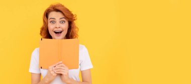 Şaşırmış bir kız sarı arka plan ve okul defterini tutuyor. İzole edilmiş yüz portresi, kopyalama alanı olan pankart