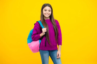 Okul üniformalı, sırt çantalı bir kız. Sarı izole edilmiş genç kız öğrenci. Öğrenim ve eğitim çocukları