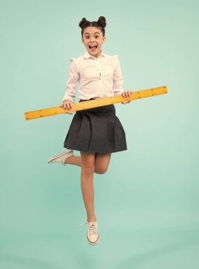 Geometri dersi için ölçü alan liseli kız. Boyunu ölçüyorum. Ölçüm aletleri. Çocuk öğrenci matematik okuyor. Mutlu pozitif ve gülümseyen okul kızı