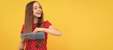 Mutlu çocuk sarı arka planda uzun saçlarını tarıyor, saç bakımını yapıyor. Çocuk saç bakımı, yatay poster. Kopyalama alanı olan başlık