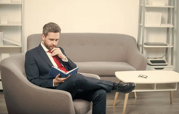 mature businessman in suit sit in office making notes in notebook.