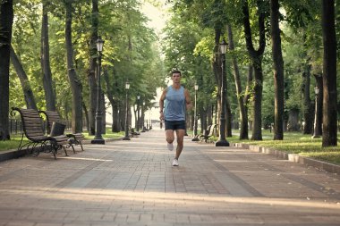 Spor kıyafetleri içinde koşan fit vücutlu atletik bir koşucu..