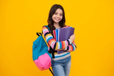 Back to school. Teenager schoolgirl hold book and copybook ready to learn. School children on isolated yellow studio background. Happy teenager, positive and smiling emotions of teen girl