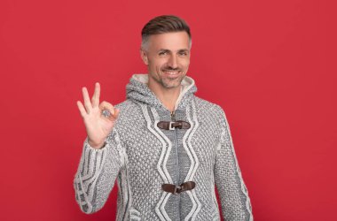 Mutlu yakışıklı adam kırmızı arka planda süveter giyer..