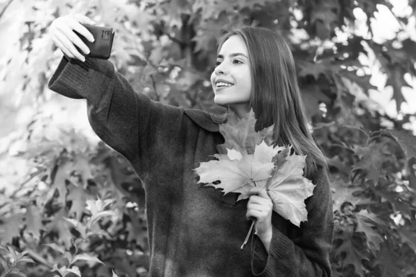 autumn nature. beautiful face portrait. natural beauty. fall season fashion. girl making selfie with autumn leaves. happy woman hold smartphone.