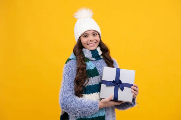 Teenager child in winter wear holding gift boxes celebrating happy New Year or Christmas. Winter kids holiday. Happy girl face, positive and smiling emotions