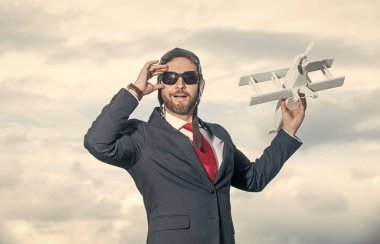 Takım elbiseli neşeli iş adamı ve pilot şapkalı uçak oyuncağı..