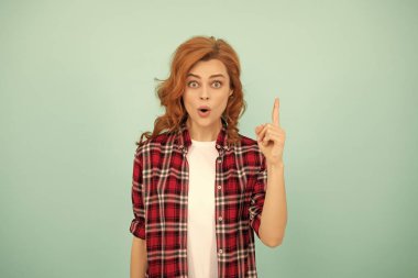 Mavi arka planda kareli tişörtlü, etkileyici kızıl saçlı kız..