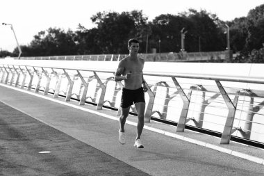 Kaslı gövdesiyle koşan atletik bir adam..